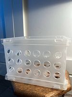Side view of transparent Sterilite storage container showing circular holes and integrated handle.