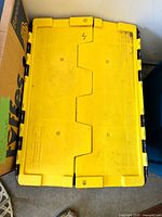 Top view of the yellow lid showing interlocking sections and locking tabs.