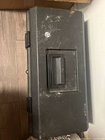 Closed black plastic toolbox with handle and latches, showing some white residue and wear.