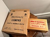 Two wooden boxes placed on a wooden stool, showing top of boxes with printed text visible