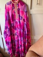 Front view of the vintage floral dress with pink, purple, and red tones showing the long sleeves and ruffled collar with crochet accents.