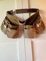 Full view of the vintage adjustable brown leather and canvas work belt with multiple tool pockets and pouches.