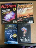 Top view of four astronomy-related books and magazines showing titles and cover designs on a flat surface