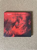 Front cover of the Rush Clockwork Angels CD showing red sky with symbolic clock face icons.