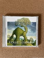 Front of CD case showing album art of a green tree-like creature and the title Scale the Summit The Migration.