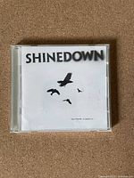 Front cover of the Shinedown CD album 'The Sound of Madness' showing the band's name and black bird silhouettes on white background.