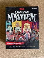 Front view of Dungeons & Dragons Dungeon Mayhem card game box showing title and four character illustrations.