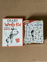 Front covers of Diary of a Wimpy Kid DVD and the Collectors Edition Uno card game box featuring respective branding and artwork.