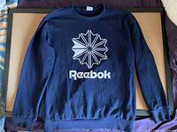 Front view of navy blue Reebok Classic long sleeve sweatshirt with white logo and text