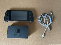 Nintendo Switch console, dock and white charging cable laid on a flat surface