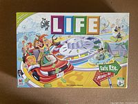 The front of The Game of Life game box showing colorful cartoon characters, car, spinner and game signs Safe Route and Risky Route.