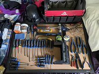 Overview of hand tools including screwdrivers, pliers, hammers, tape measures, safety glasses, and a red and black Husky fabric toolbox.