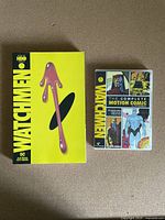 Front covers of both the Watchmen graphic novel and the motion comic set, showing iconic artwork and bright yellow theme.