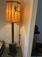 Both floor lamps side by side; wood column with glass table and brass adjustable lamp visible