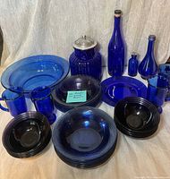 Full lot overview showing bowls, plates, bottles, mugs, lidded jar