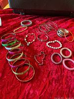 Overview of assorted bangles, bracelets and watches on red fabric