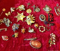 Overview of assorted pins, brooches and pendants on red background