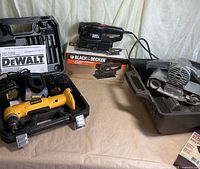 DeWalt drill set, Black & Decker sander, Craftsman belt sander displayed together