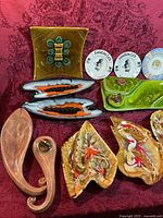 Group of ashtrays showing square olive piece, fish pair, boomerang, drip glaze leaves, souvenir rounds