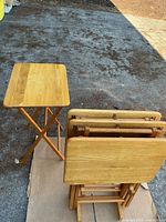 Set showing one tray table open and three folded on stand