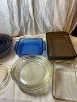 Overall view: cobalt blue square casserole, brown rectangular casserole, clear loaf pan, stack of clear pie plates