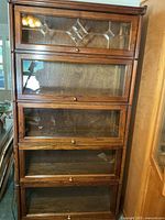 Front view of entire oak barrister bookcase showing five glass doors, leaded glass top panel, brass knobs