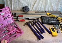 overview of lot showing pink tool kit, purple hammers, bar clamps, socket set, level, stud finder, padlock, auger bit