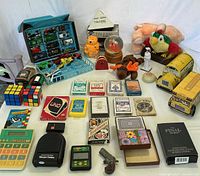 Overview of mixed lot displaying toys, cards, puzzles, electronics and plush items