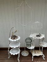 Two cast iron plant stands, tall birdcage stand, three birdcages
