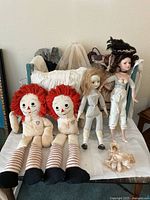 Group shot of all dolls and crib on table