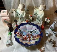 Overview showing porcelain figurines, bowl, sake ware, wooden dolls and additional decor items