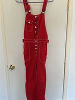 Full view red cotton overall hanging on door