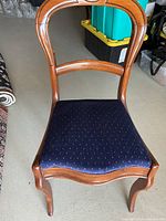 Front view of one chair showing curved wooden back and blue upholstered seat with dotted pattern