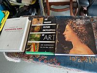 Three art books laid out on a table showing front covers: History of Modern Art, The Praeger Picture Encyclopedia of Art, and The Metropolitan Museum of Art.