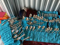 Flatware laid out on turquoise cloth, showing multiple forks.