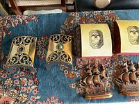 Top view showing brass bookends with black enamel scrollwork and pairs of ship bookends with original boxes.