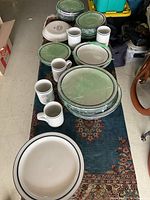 Overall view of stacked plates, bowls, and mugs on a table.