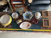 Photo showing the entire lot on table including glassware, ceramics, and framed prints.