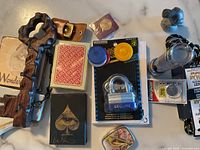 Overview of miscellaneous items including playing cards, padlock, chips, wooden rack, flashlight, batteries, and pink carved stone.