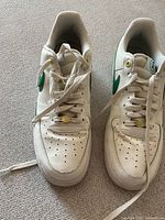 Pair of vintage white Nike Air running shoes with green swoosh logos placed side by side, showing wear and use.