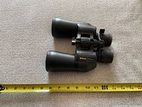 Top view of Nikon Action binoculars showing brand and model markings with measuring tape for scale.