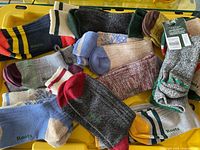 Multiple pairs of Roots brand new socks in assorted colors and patterns laid out on a yellow surface.