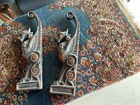 Pair of copper griffin statues shown side by side on patterned rug.