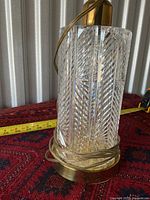 Side view of the glass and brass base of the lamp with a measuring tape showing approximately 14 inches height.