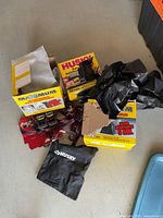 Boxes of Husky contractor trash bags (3 mil and 5 mil thickness) and several tie downs in red and black with metal ratchets.