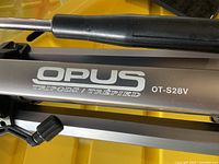 Close-up of tripod branding showing Opus OT-S28V model name and logo on leg.