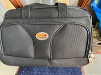 Front view of black VIA Rail Canada travel bag with handles and front pocket featuring VIA Rail Canada logo badge.