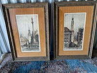 Photo of set of two framed engraved plates depicting architectural scenes, displayed side by side on floor.