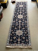 Full-length view of rug from one end showing overall pattern, fringe and coloration