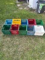 Ten plastic milk crates arranged on grass